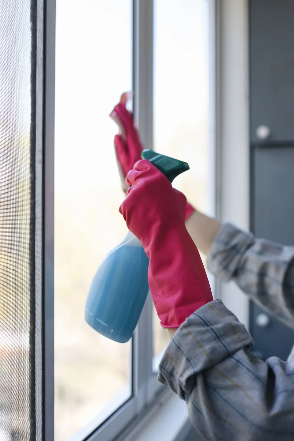 Rengöring av ett fönster med sprayflaska och handskar.